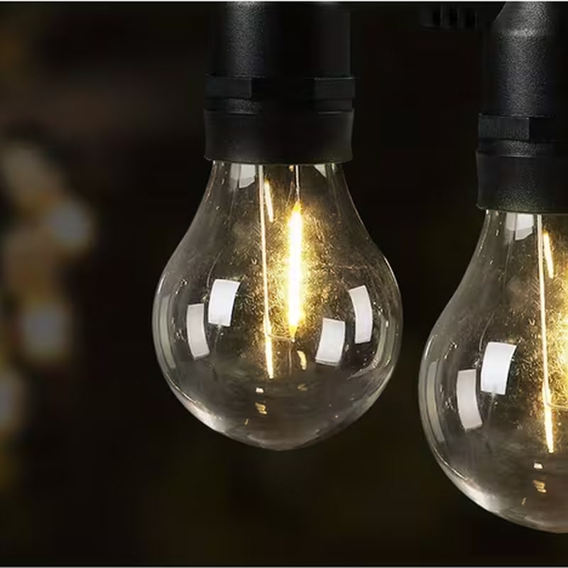 Warm white 2700K festoon light bulbs glowing at night over an outdoor event